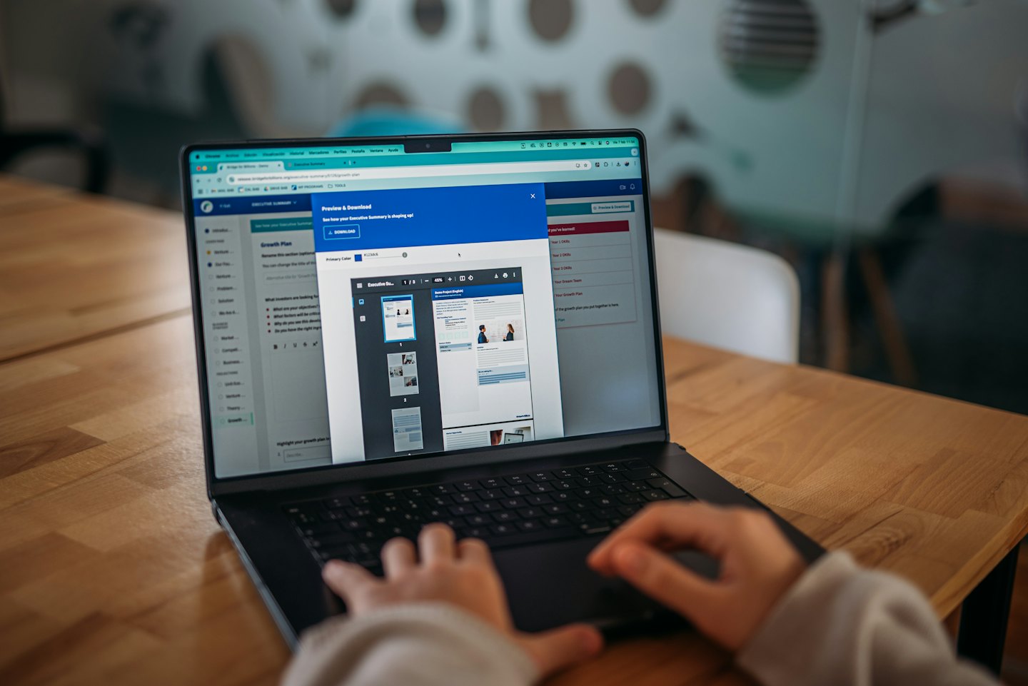 Hände tippen auf einem Laptop, der eine Dokumentenvorschau anzeigt.